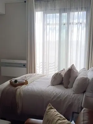a large bed with white pillows and a window at Studio in Menlyn Maine in Pretoria