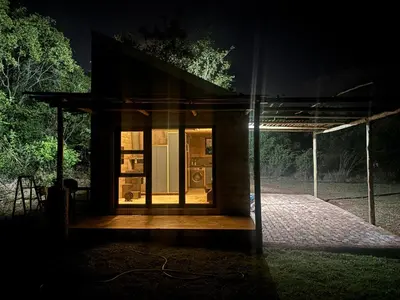 a small house with a glass door at night at Bosch Rest in Pretoria