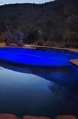 a blue pool of water with a mountain in the background at A Farm Experience at Shoulder Mountain Products in Vaalwater