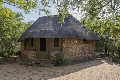 a small stone house with a thatched roof at A Farm Experience at Shoulder Mountain Products in Vaalwater