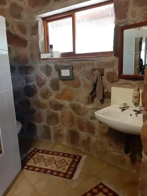 a stone bathroom with a sink and a mirror at A Farm Experience at Shoulder Mountain Products in Vaalwater