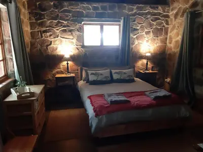 a bedroom with a bed with a stone wall at A Farm Experience at Shoulder Mountain Products in Vaalwater