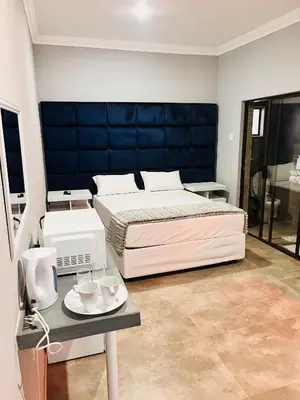 a bedroom with a bed and a table with cups at Dzire Guesthouse in Thohoyandou
