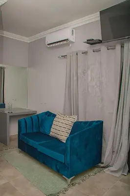 a blue couch sitting in a living room next to a curtain at Dzire Guesthouse in Thohoyandou