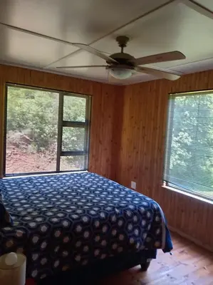 a bedroom with a bed and a ceiling fan at Barberton Troop Cabin in Barberton