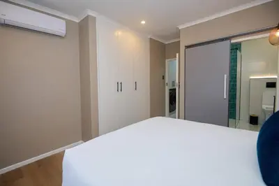 a bedroom with a white bed and a sliding glass door at Unit 109 at Glen Park in Pretoria