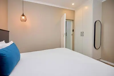 a bedroom with a large white bed with a blue pillow at Unit 109 at Glen Park in Pretoria