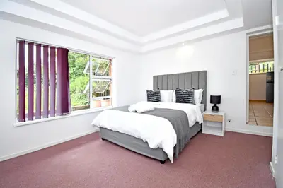 a white bedroom with a large bed and a window at Sandton Elite Stay in Sandton