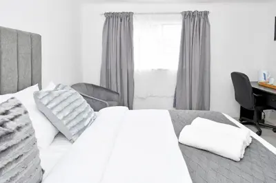 a bedroom with a white bed and a desk at Sandton Elite Stay in Sandton