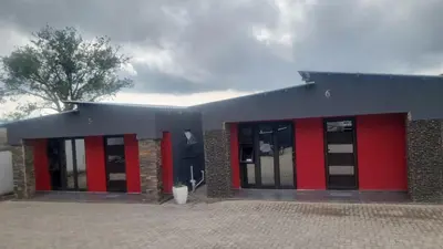 a building with red and black doors and a tree at Vegas guest house in Dwarsloop