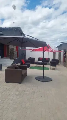 a patio with couches and an umbrella at Vegas guest house in Dwarsloop