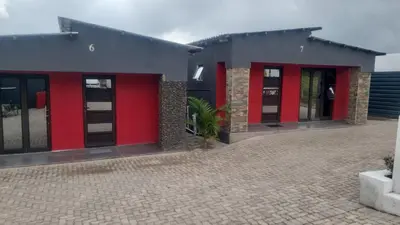 a building with red doors and a brick courtyard at Vegas guest house in Dwarsloop
