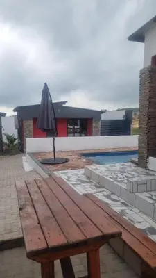 a wooden picnic table with an umbrella next to a pool at Vegas guest house in Dwarsloop