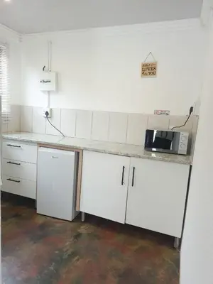 a kitchen with white cabinets and a counter with a microwave at Vegas guest house in Dwarsloop