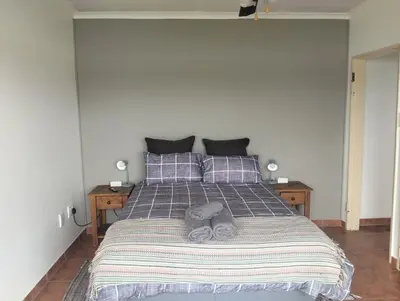 a bedroom with a bed with a striped blanket and pillows at Witbank Dam Self Check In in Witbank