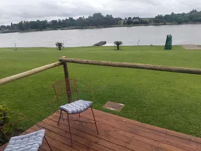 a chair sitting on a deck next to a body of water at Witbank Dam Self Check In in Witbank