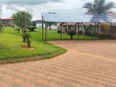 a brick road with a building with a solar roof at Witbank Dam Self Check In in Witbank