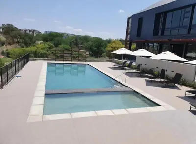 a swimming pool on a building with chairs and umbrellas at Cosy 1 bedroom Apartment in Midrand