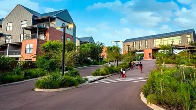people crossing a street in front of a building at Cosy 1 bedroom Apartment in Midrand