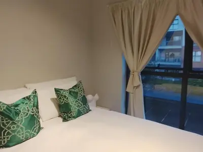 a bed with two green pillows and a window at Cosy 1 bedroom Apartment in Midrand