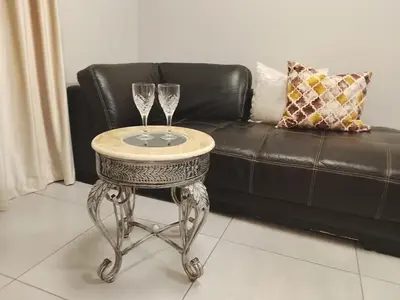a table with two wine glasses on it next to a couch at Cosy 1 bedroom Apartment in Midrand
