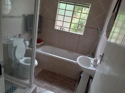 a bathroom with a tub and a toilet and a sink at Nested at L&M in Centurion