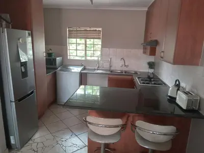 a kitchen with a sink and a counter with two stools at Nested at L&M in Centurion
