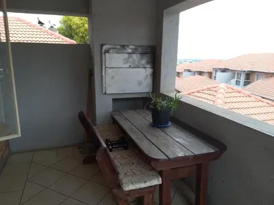 a wooden table and a potted plant on a balcony at Nested at L&M in Centurion