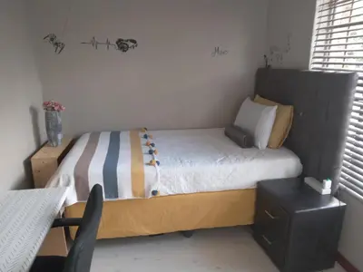 a small bedroom with a bed with a wooden headboard at Nested at L&M in Centurion