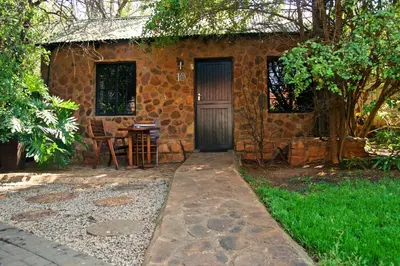a stone house with a door and a table at Khayamanzi Guesthouse in Hartbeespoort