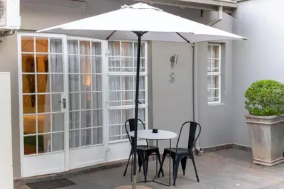a table and chairs under an umbrella on a patio at Khayamanzi Guesthouse in Hartbeespoort