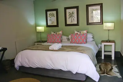 a bedroom with a large bed with red pillows at Khayamanzi Guesthouse in Hartbeespoort