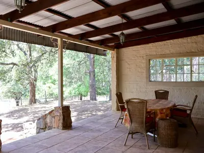 a patio with a table and chairs and a large window at Winnaarspoort Lodge in Machadodorp