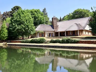 a house with a pond in front of it at Winnaarspoort Lodge in Machadodorp