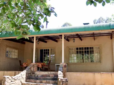 a house with a green roof and some stairs at Winnaarspoort Lodge in Machadodorp