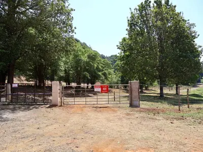 a gate in a field with trees in the background at Winnaarspoort Lodge in Machadodorp