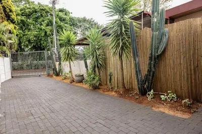 a fence with palm trees next to a sidewalk at Thorne's crip in Pretoria