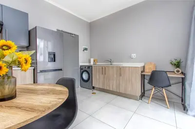 a kitchen with a table and a kitchen with a dishwasher at WiFi, Washer, Smart TV, Balcony & Pool in Midrand