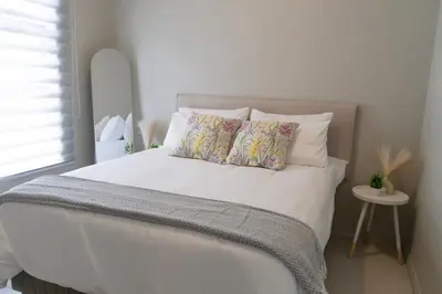 a bed with white sheets and pillows in a bedroom at WiFi, Washer, Smart TV, Balcony & Pool in Midrand