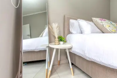 a bedroom with a bed and a table with a mirror at WiFi, Washer, Smart TV, Balcony & Pool in Midrand