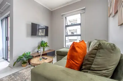 a living room with a couch and a table at WiFi, Washer, Smart TV, Balcony & Pool in Midrand