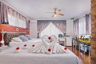 two swans dressed in white are sitting on a bed at Lodge At The Link in Kempton Park