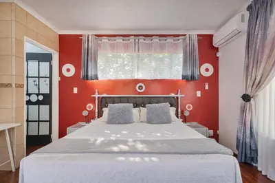 a bedroom with a large bed with a red wall at Lodge At The Link in Kempton Park