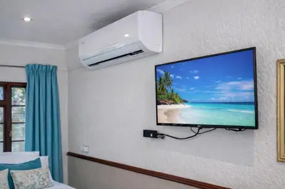 a flat screen tv hanging on a wall in a room at Lodge At The Link in Kempton Park