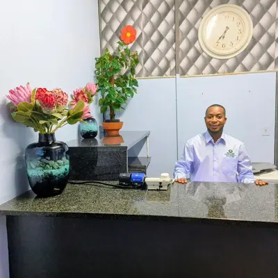 a man standing behind a counter in a room with flowers at Africa Lodges in Thabazimbi