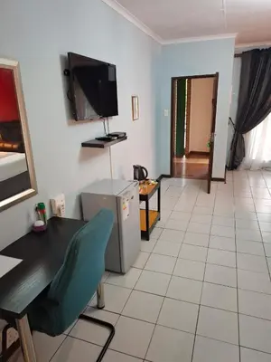 a living room with a table and a tv on the wall at Africa Lodges in Thabazimbi