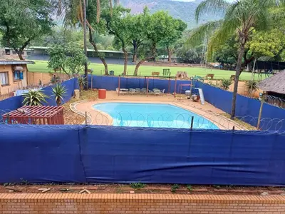a swimming pool with a blue fence around it at Africa Lodges in Thabazimbi