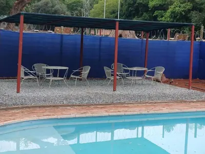 a table and chairs next to a swimming pool at Africa Lodges in Thabazimbi