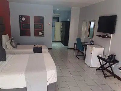 a hotel room with a bed and a flat screen tv at Africa Lodges in Thabazimbi