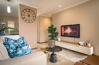 a living room with a couch and a clock on the wall at Entire Modern Comfortable Lux Centurion Apartment in Pretoria